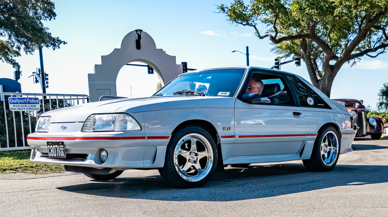 Front 3/4 view of white and red Fox Body Ford Mustang GT at car show.