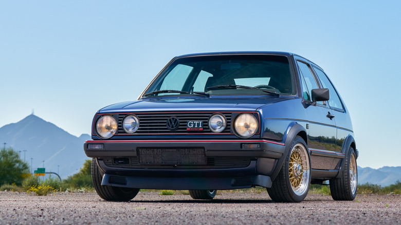 Front 3/4 view of 1987 Volkswagen Golf Mk2 GTI parked in front of mountains.