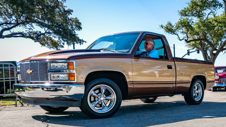 Front 3/4 view of gold Chevy SIlverado OBS pickup truck at car show.