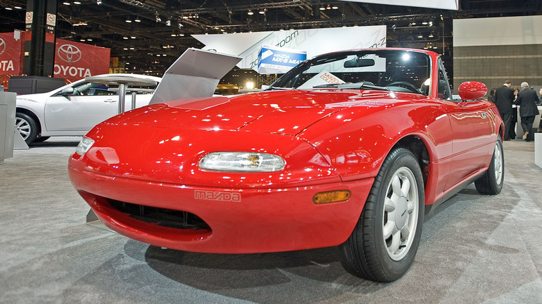 Red 1990 Mazda Miata parked at auto show.