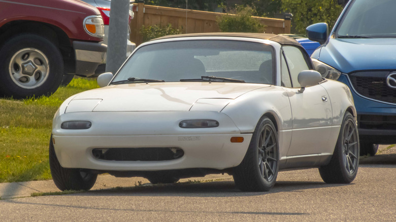 Front view of white NA Mazda Miata parked on street.