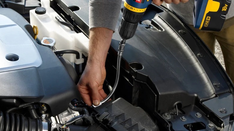 A person working on a car with a Ryobi power drill and the Ryobi Flexible Shaft Bit Holder.