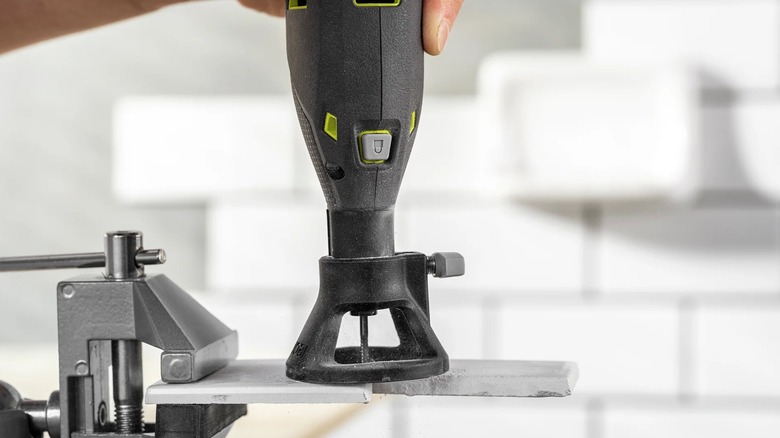 A person cutting tile with a Ryobi rotary tool and the Tile Cutting Rotary Kit.