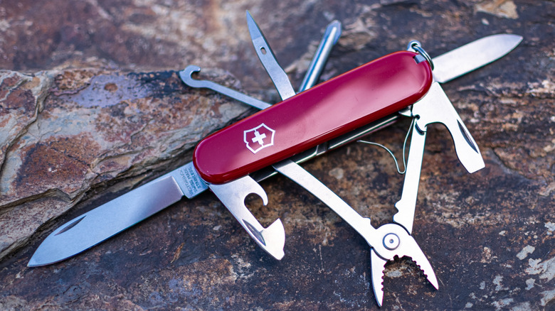 Victorinox Spartan folding Swiss Army knife on stone background. Tools have been pulled out to view, including the blade, hook, can opener and screwdriver.