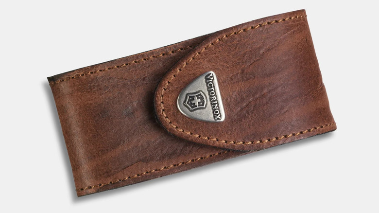 A brown leather pouch displayed sideways. It has brown stitching around the edge and a silver shield-like design that says Victorinox and has a Swiss Cross logo