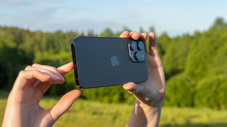 Hands holding an iPhone 14 Pro Max in the outdoors