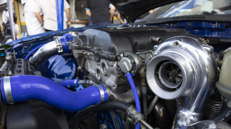 Close-up of customized inline engine with turbo featuring blue intake and hoses