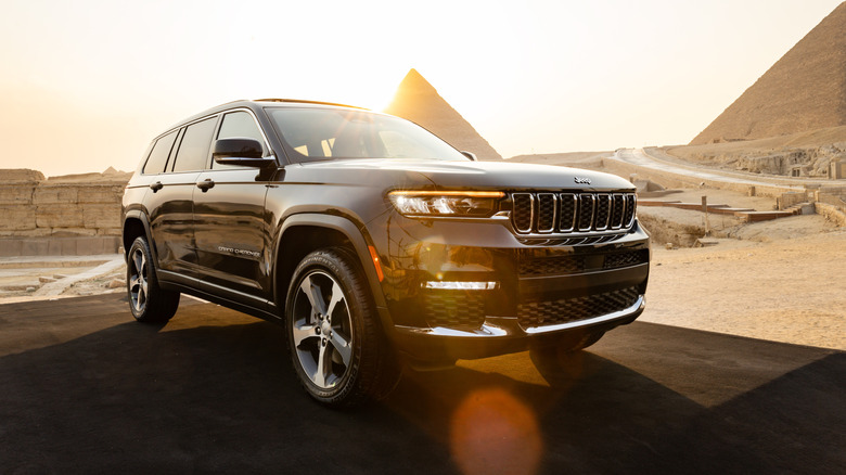 The Jeep Grand Cherokee seen from left front, in a desert with pyramids in the background.