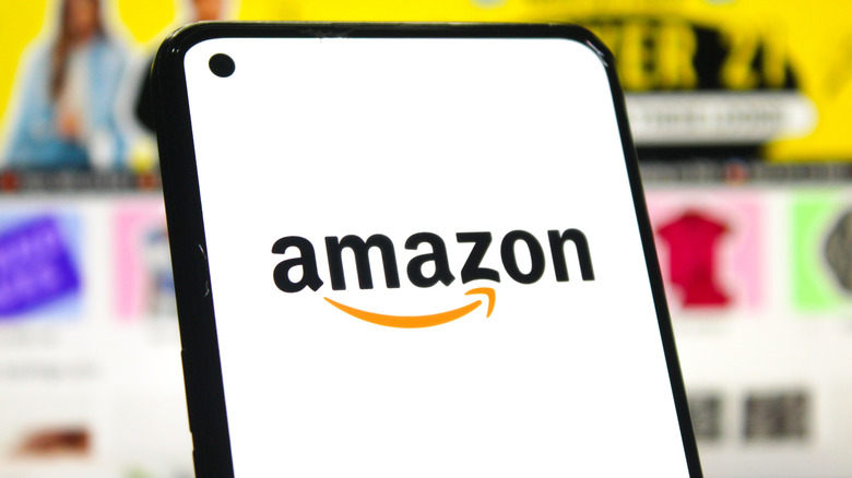 Amazon logo on a smartphone with website as the background
