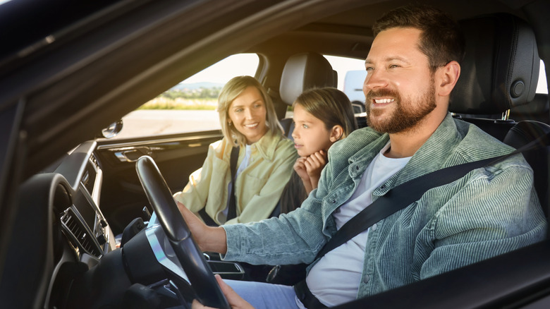 Smiling man driving his family in a car