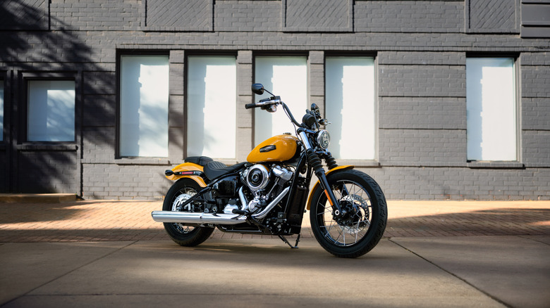 A yellow and chrome 2025 Harley Street Bob parked in front of a grey building