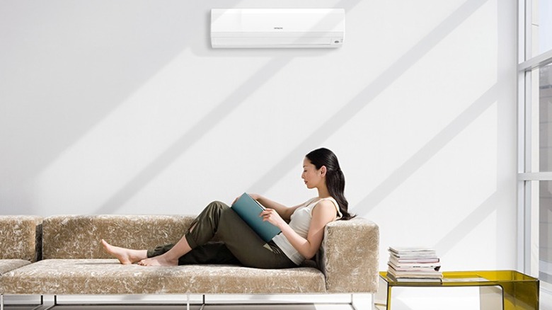 Hitachi AC on wall, person relaxing on a couch directly below