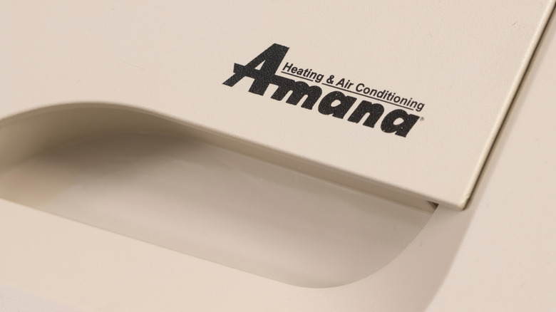 A close-up image of the Amana Heating and Air Conditioning logo printed on a beige appliance.
