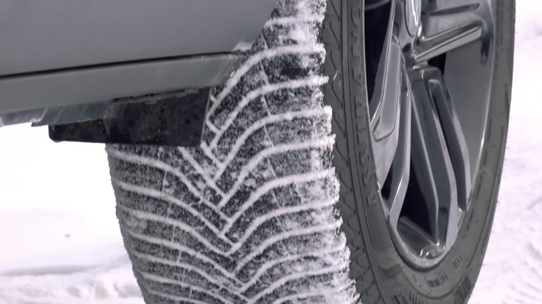 Close-up of vehicle wheel and tire with snowy treads.