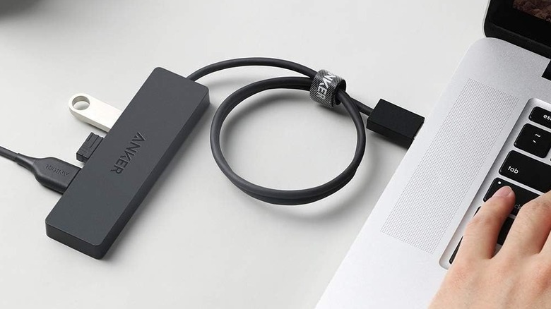 An Anker 4-pourt USB hut plugged into a silver laptop