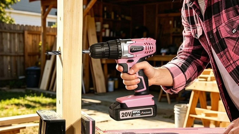 A person in a pink plaid shirt using the Avid cordless drill