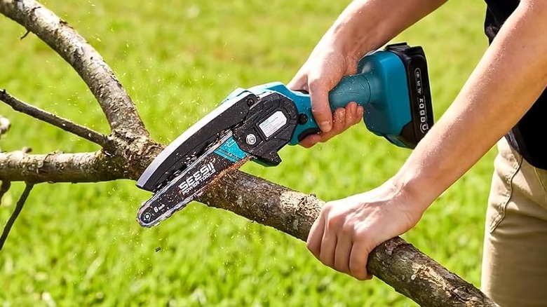 A person using the Seesii mini chainsaw on a tree branch