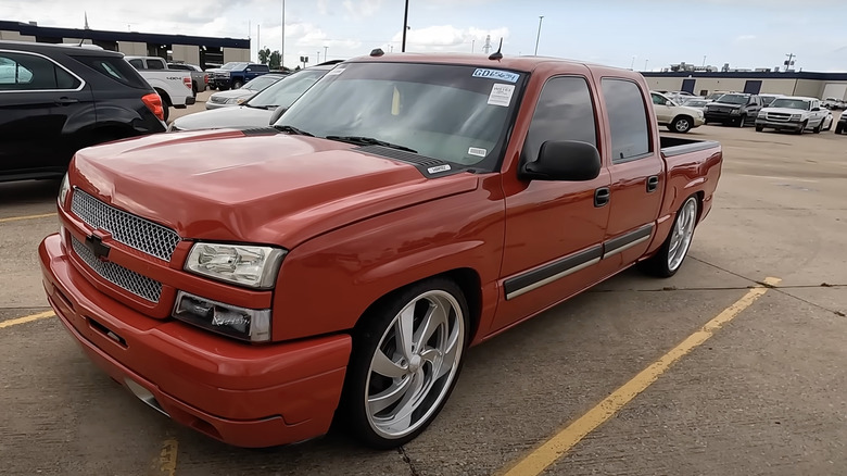 A 2006 Red Chevy Silverado lowrider parked at an auction