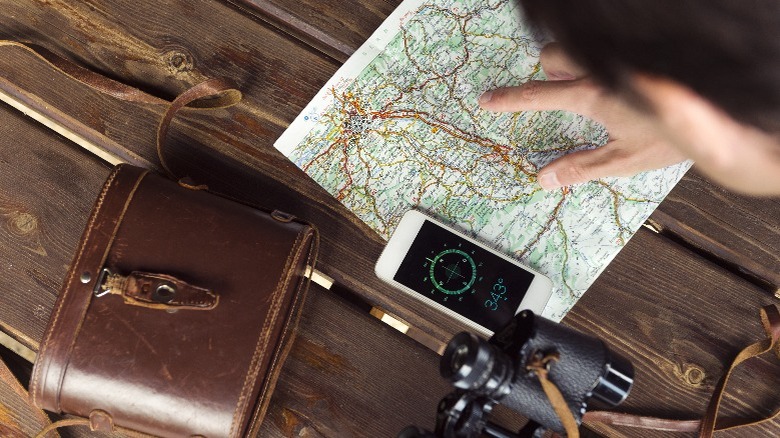 Person using a compass app and a map