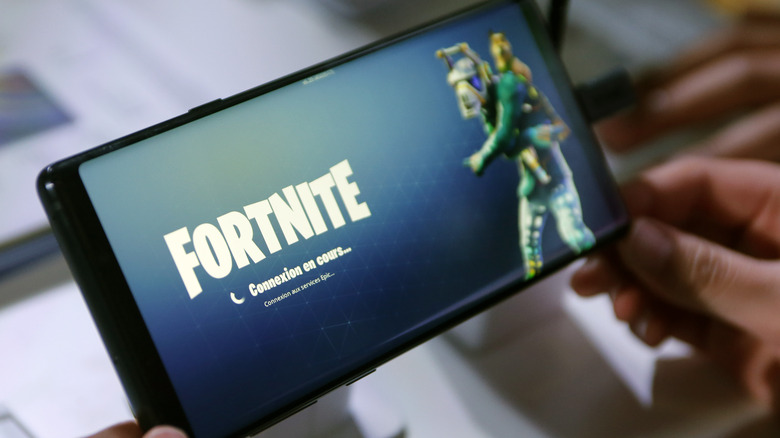 Person holding phone with Fortnite