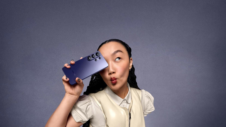 A girl holding the Samsung S26 Ultra against a gray studio background