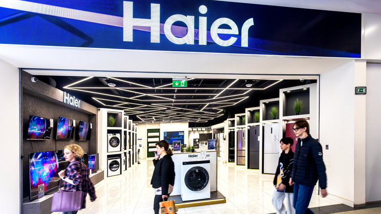People walking in front of Haier appliance retail store.
