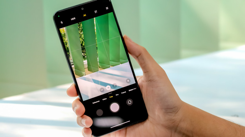 A hand holding a phone with the camera app opened