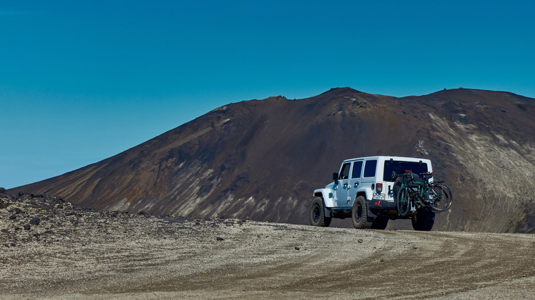 A white Jeep in the distance with two bikes mounted on its back