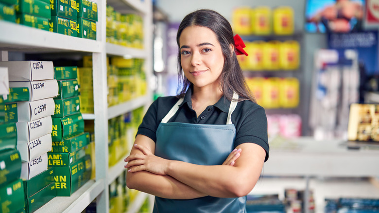 A retail worker standing in front of a shelf full of auto parts.