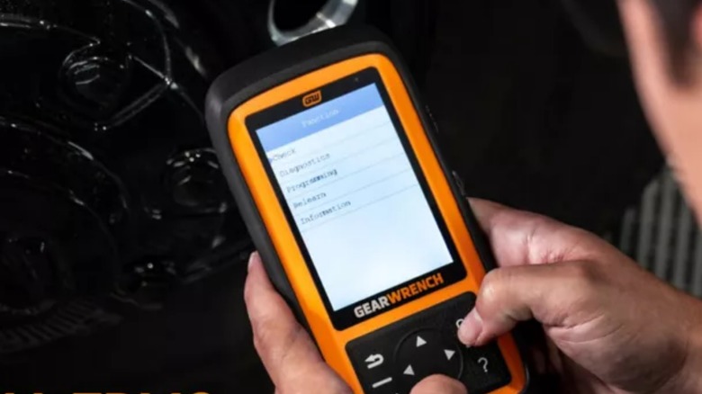 A person using a Gearwrench TPSM tool in a car.