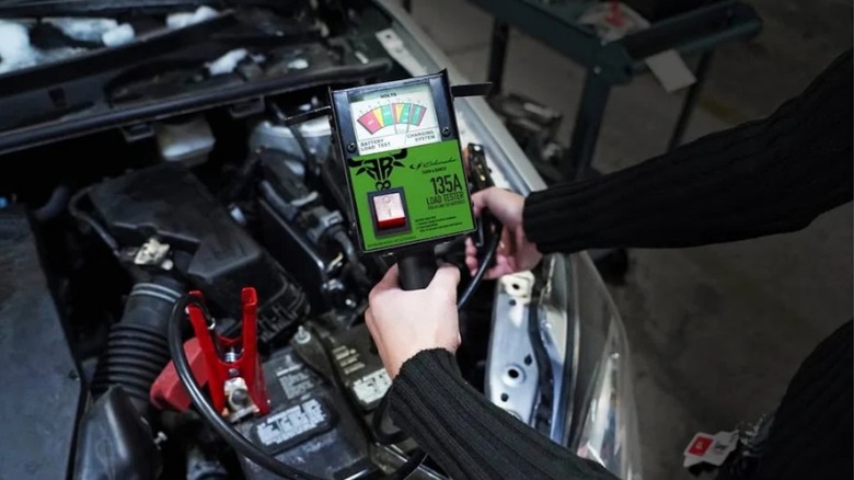 A person using a battery tester on a car.