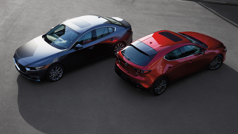 Front 3/4 view of Mazda3 sedan and rear 3/4 view of Mazda3 hatchback parked in street setting