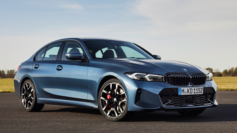 Front 3/4 view of BMW 3-Series parked on tarmac in forested setting