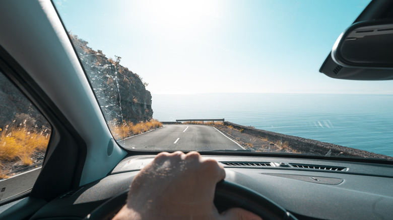 Hand on a steering wheel with windshield view