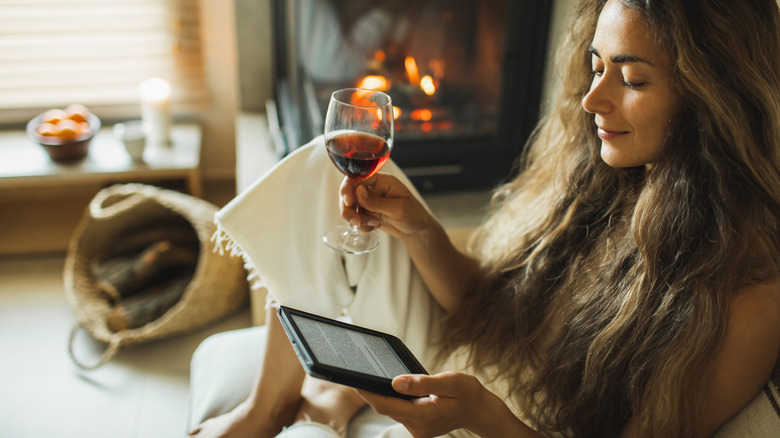 Woman drinking wine reading e-reader