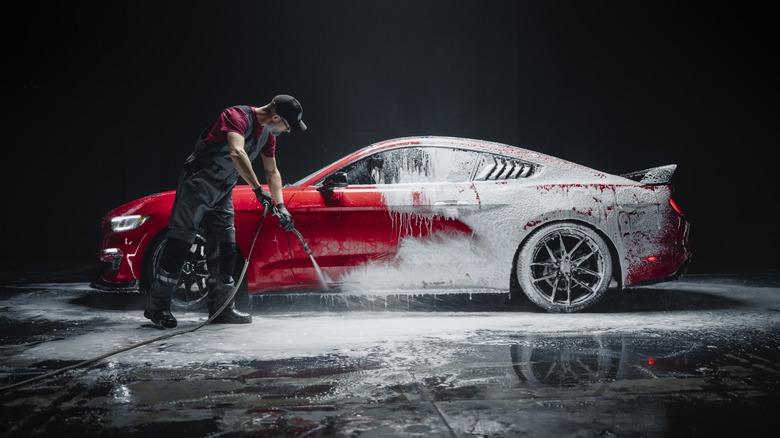 Adult male washing a red sports car