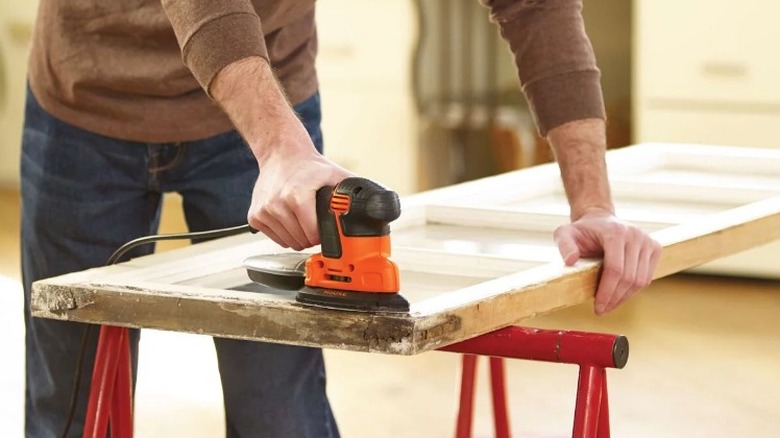 Person sanding door with Black and Decker mouse sander