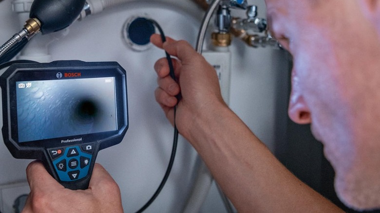 man using bosch inspection camera in pipe