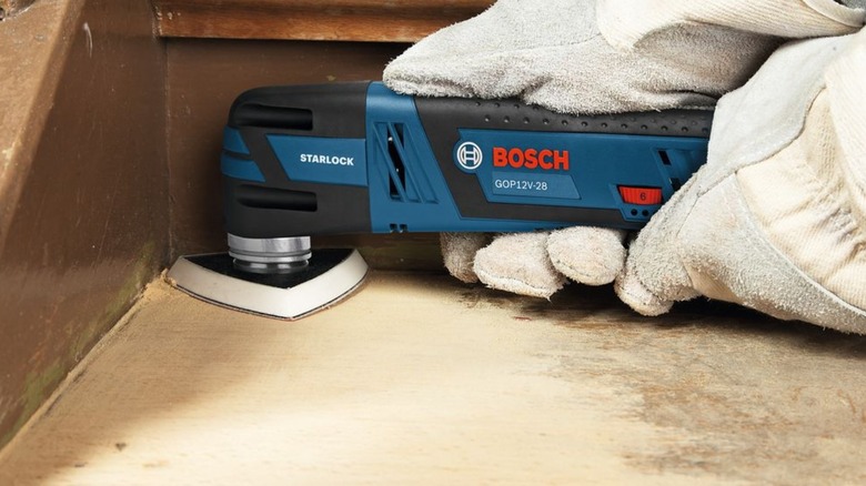 A person sands stairs with a Bosch oscillating multi-tool.