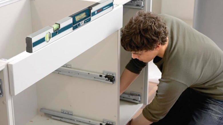 A person builds a desk using the Bosch digital level.