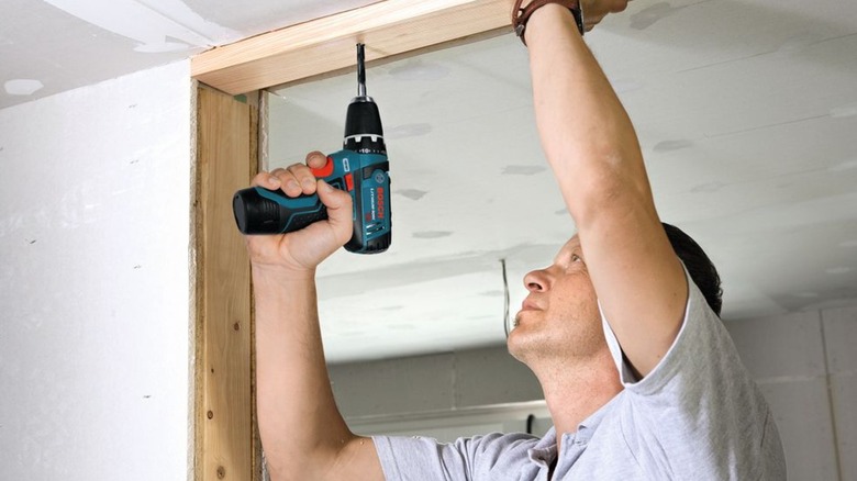 A man using the Bosch 3/8 inch drill/driver in a ceiling.