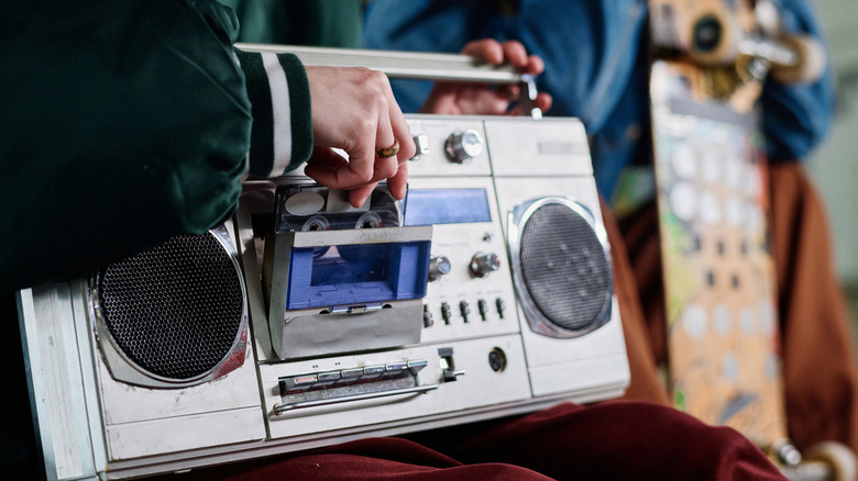 A silver boombox that someone is loading a tape into.