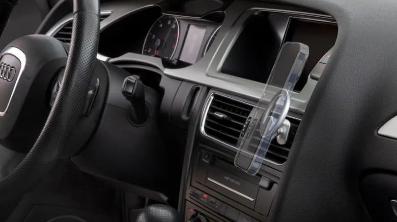 An image showing how a phone holder mounted on the vent of a car dashboard would hold a phone