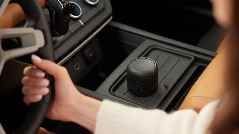 The center console of a car featuring a round, black device placed on it