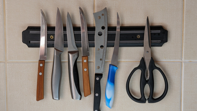 Knives and scissors hanging from a magnetic strip