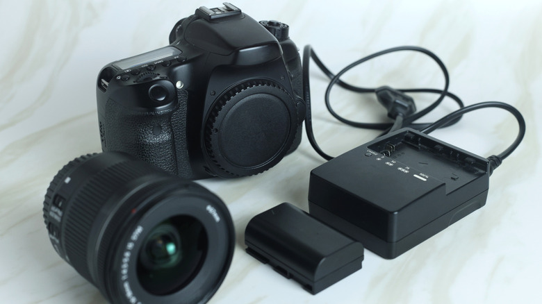 A DSLR camera placed on top of a table along with its accessories