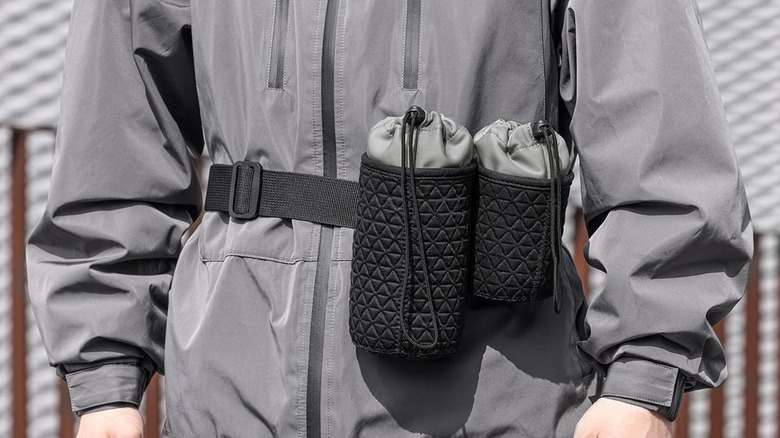 Lens pouches attached to someone's body with a belt strap.