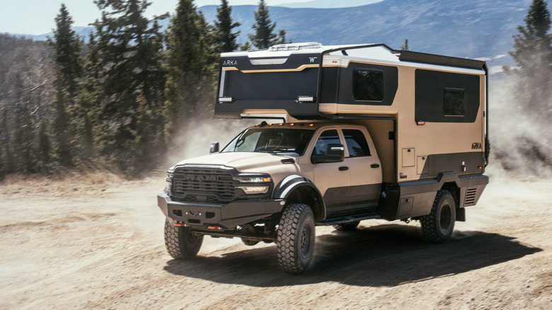 2026 Winnebago ARKA driving in forested terrain, front-left 3/4 view