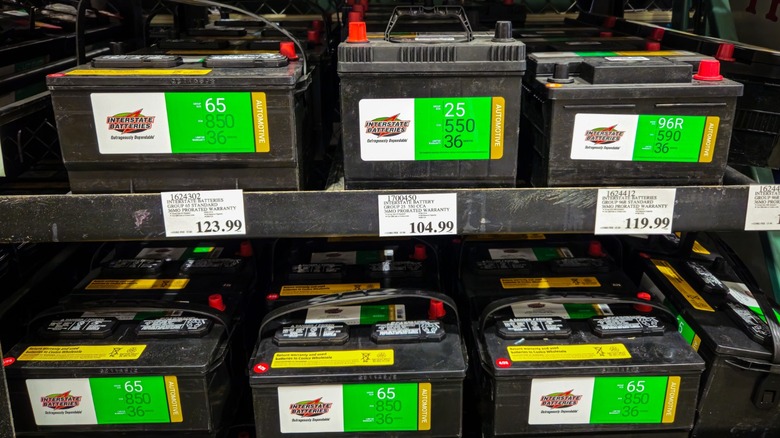 Shelves stocked with various Interstate car batteries on display with price tags in a store