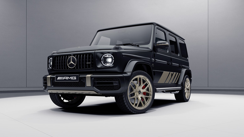 A Mercedes-AMG G63 Grand Edition in a studio setting, front 3/4, black exterior with gold details